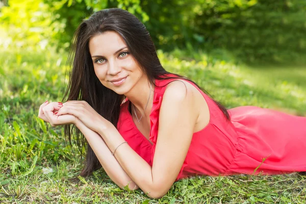 Açık havada mutlu ve gülümseyen çimenlerin üzerinde rahatlatıcı güzel kadın.