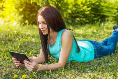 Çim üzerinde yalan ve tablet kullanarak genç kadın