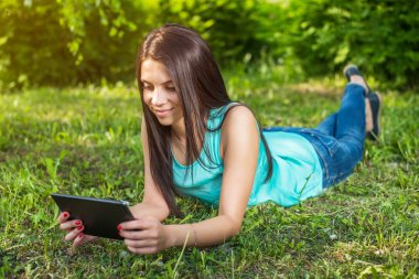 Çim üzerinde yalan ve tablet kullanarak genç kadın