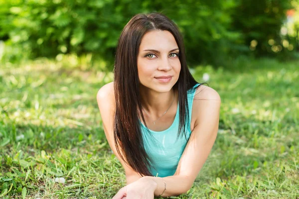 Beautiful woman relaxing outdoors on grass looking happy and smiling. — Stock Photo, Image