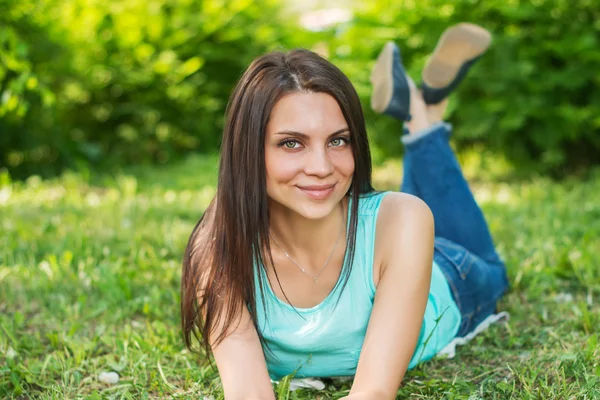 Beautiful woman relaxing outdoors on grass looking happy and smiling. — Stock Photo, Image