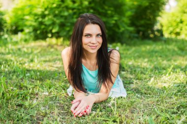 Açık havada mutlu ve gülümseyen çimenlerin üzerinde rahatlatıcı güzel kadın.