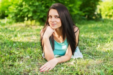 Açık havada mutlu ve gülümseyen çimenlerin üzerinde rahatlatıcı güzel kadın.