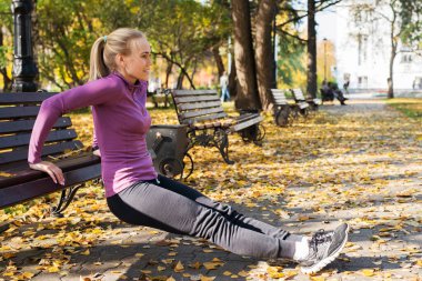Genç kadın parkta şınav egzersizi yapıyor. Sonbaharda dışarıda spor..