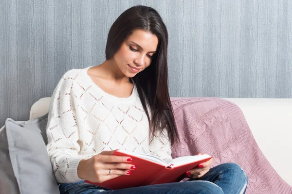 Jovem mulher sentada ler sofá sofá livro em casa — Fotografia de Stock