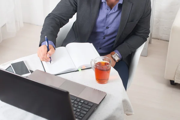 Empresario en la oficina sentado en una mesa con un ordenador portátil escribe con concentración . —  Fotos de Stock