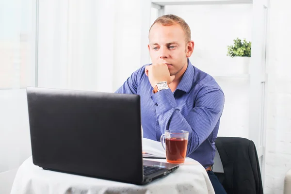 Empresario trabajando en la oficina, sentado en una mesa sosteniendo la taza y mirando recto — Foto de Stock