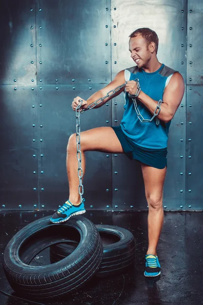 Des sportifs. ajustement malestands avec un pied sur la chaîne de fer de pneu et des larmes, concept Crossfit fitness entraînement force puissance — Photo