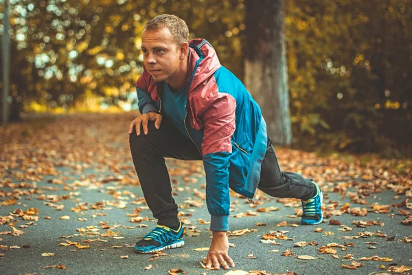 Спортсмен розтягується в парку осінь, роблячи вправи. Фітнес-концепції — стокове фото