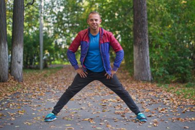 spor adamı park sonbahar germe egzersizleri yapıyor. Fitness kavramları.