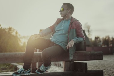 Çekici erkek spor akşam gün batarken Beach üzerinde oturan.