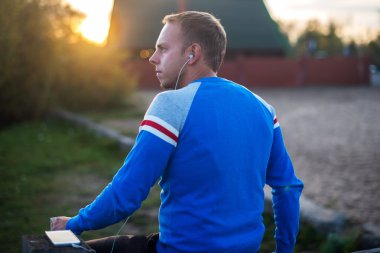 Çekici erkek spor akşam gün batarken Beach üzerinde oturan.