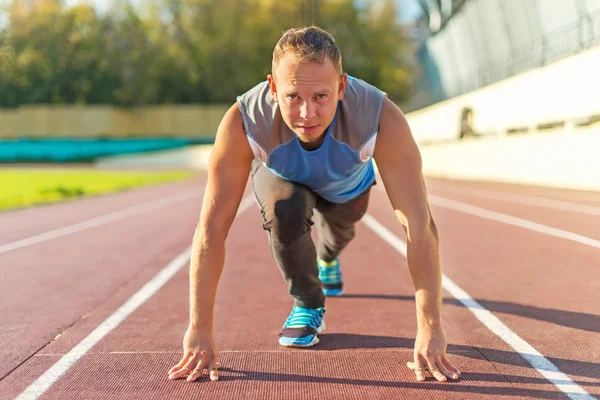 Hombre atlético de pie en postura listo para correr en una cinta de correr . — Foto de Stock