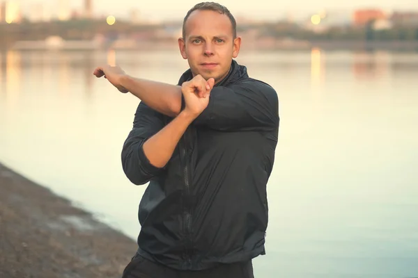 Hombre atlético haciendo ejercicio en la playa al atardecer al aire libre . — Foto de Stock