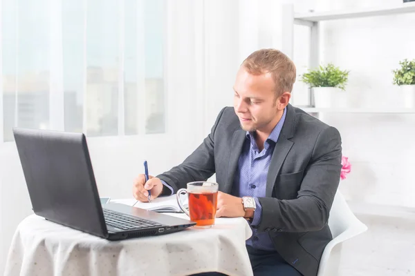 Geschäftsmann im Büro sitzt mit Laptop am Tisch und schreibt konzentriert — Stockfoto