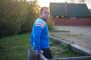 Çekici erkek spor akşam gün batarken Beach üzerinde oturan.