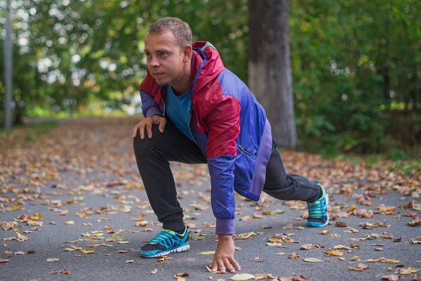 Homem do esporte que estica no outono do parque, fazendo exercícios. Conceitos de aptidão — Fotografia de Stock
