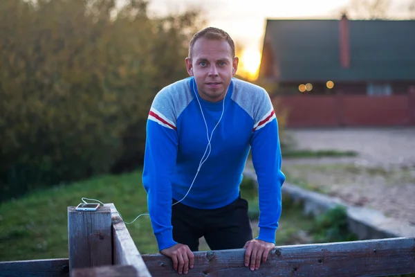 Vonzó az ember ül a strandon az esti naplemente után sport. — Stock Fotó