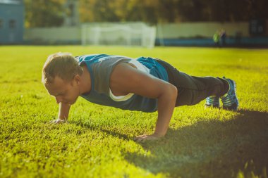 bir güneşli gün çimenlerin üzerinde şınav spor erkek parkta, germe. Fitness kavramları.