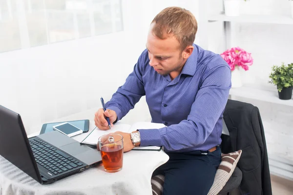Empresario en la oficina sentado en la mesa con un ordenador portátil escribe concentración — Foto de Stock