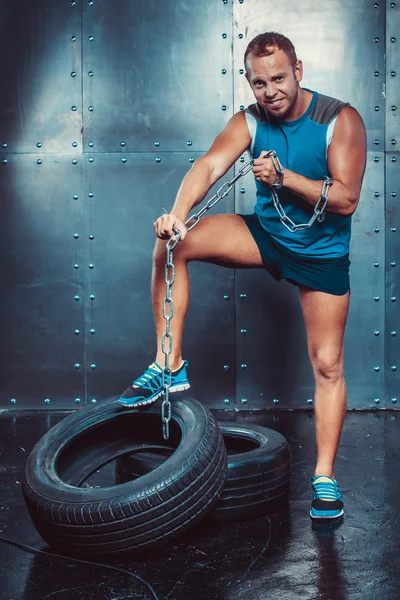 Sportolók. Fit malestands gumiabroncs vasláncot és könnyek, fogalma fitness edzés erőt hatalom lábbal. — Stock Fotó