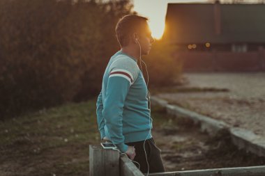 Çekici erkek spor akşam gün batarken Beach üzerinde oturan