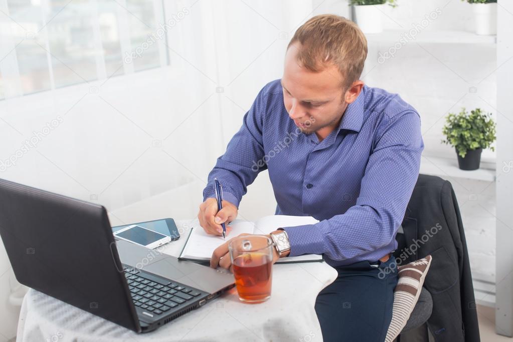 Businessman in office sitting at  table with a laptop writes concentration