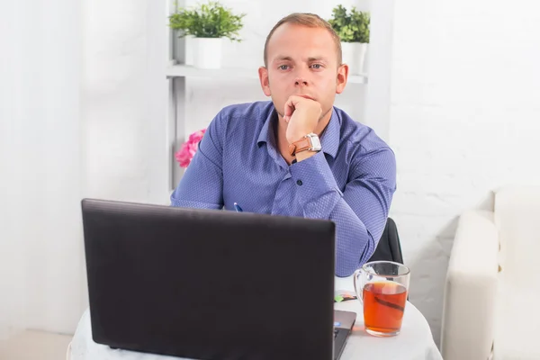 Empresario trabajando en la oficina, sentado en la mesa con un ordenador portátil, mirando a la cámara . — Foto de Stock