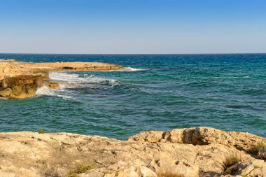 Bir yaz akşamında masmavi denizin kayalık kıyısı.