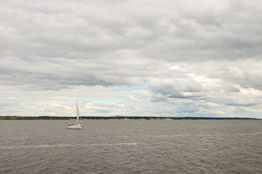 16 Ağustos 2015: Bulutlu bir günde bir yelkenli yatı nehir boyunca ilerliyor. Cheboksary 'de. Rusya.