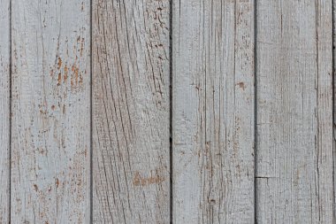 The wall is made of old painted vertical  boards with white paint coming off