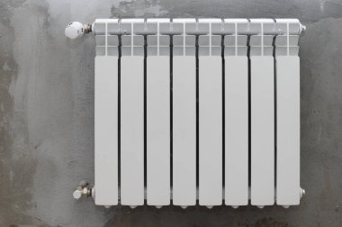 Gri bir duvarda beyaz radyatör