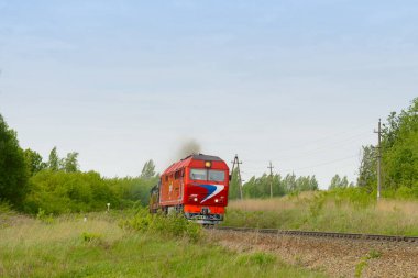 27 Mayıs 2018: Kırmızı bir lokomotif ormanın ortasındaki bir demiryolunda ilerliyor. Chuvashia. Rusya.