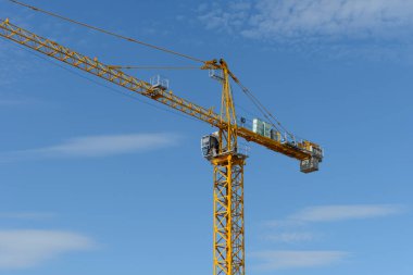 Mavi arka planda taksisi olan inşaat kulesi vinci