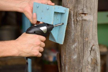 Küçük bir tornavida kullanan erkek eller tahta bir nesneyi direğe çevirir.