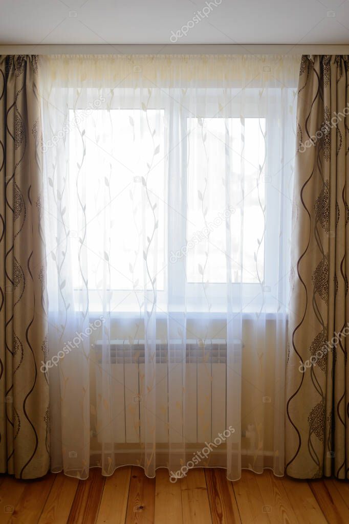 Simple dark interior of the room with wooden floors and a window with curtains