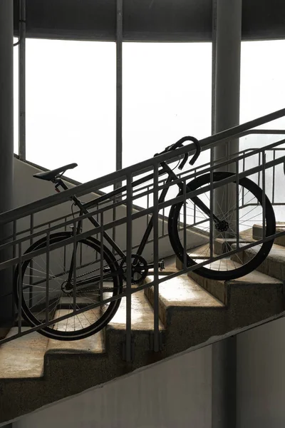 Single speed bike on the stairs against the background of light windows, vintage vertical photo