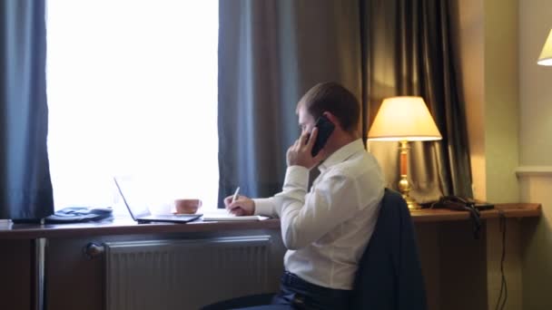 Jonge manager werken op de computer in de hotelkamer — Stockvideo