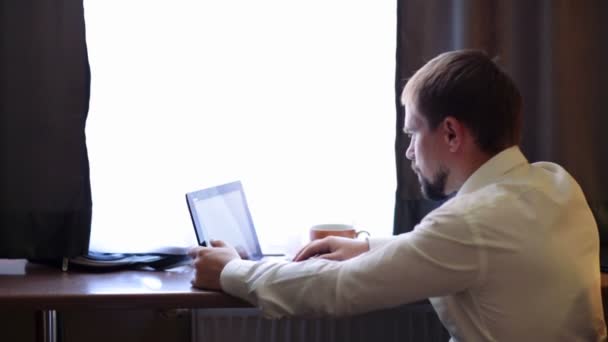 En ung sjef som jobber med datamaskinen på hotellrommet. – stockvideo