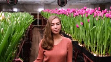 Çiçek serasında poz veren kahverengi elbiseli genç kız laleler 