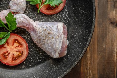 Baharatlı, maydanozlu ve tavada domatesli taze çiğ tavuk bacağı.