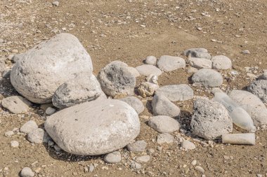 Plastik çöp, kumlu bir sahilde kayaların arasında
