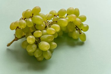 Açık yeşil bir yüzey üzerinde olgun sulu üzümler.