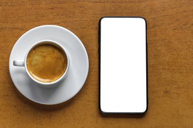 Aromatik taze kahve beyaz bir porselen fincanda ve akıllı telefon bir masada, taklit, düz uzanmış