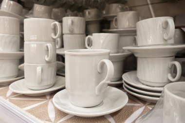 Süpermarkette beyaz bardaklar, fincanlar ve tabaklar tezgahın üzerinde.