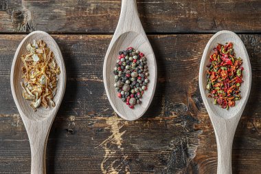 Baharatlar kurutulmuş soğanlar, çeşitli biberler ve ahşap kaşıklarda kırmızı biber taneleri.