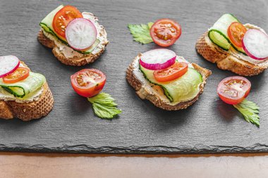 Krem peynirli, salatalıklı, turplu ve vişneli domatesli ekmek dilimleri.