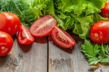 Taze çıtır marul, sulu olgun domatesler ve ahşap bir masanın üzerinde bitkiler.