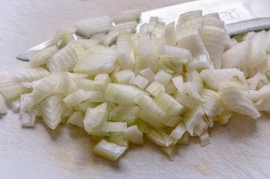 Doğranmış soğan ve beyaz kesme tahtasının üzerinde bir bıçak.