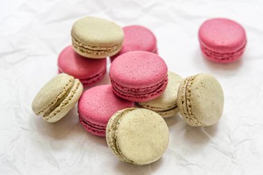 Ahududu ve şam fıstıklı kurabiyeler beyaz parşömen üzerinde.